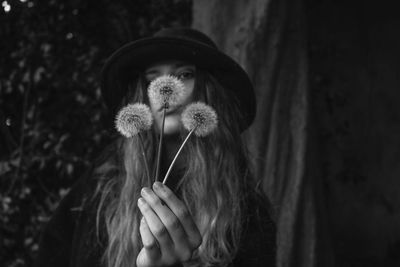 Portrait of woman holding dandelion