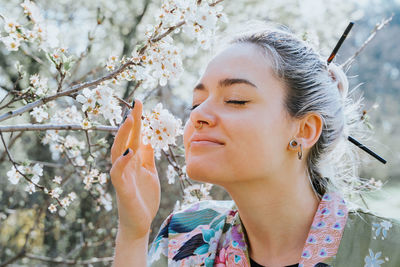 Portrait of young woman against cherry blossom