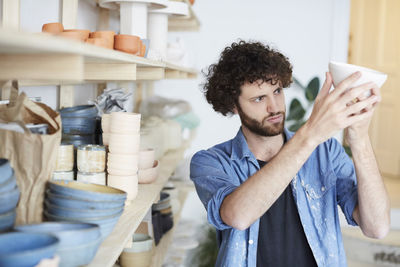 Mid adult man examining bowl in pottery class