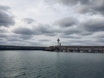 View of building by sea against cloudy sky