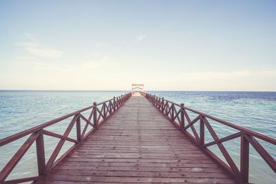 Jetty leading towards sea against sky