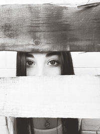 Close-up portrait of woman hiding behind curtain