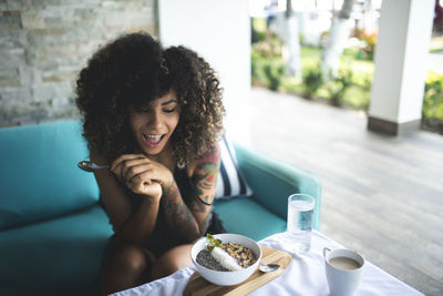 Curly haired woman having breakfast at home