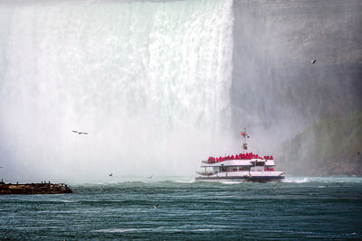 Tour boat in the mist under horseshoe falls on the niagara river