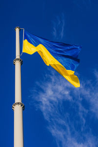 Low angle view of flags against blue sky