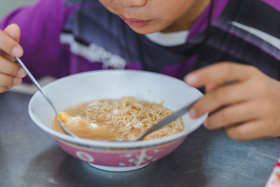 Midsection of man eating noodles in bowl