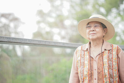 Portrait of woman wearing hat standing against blurred background