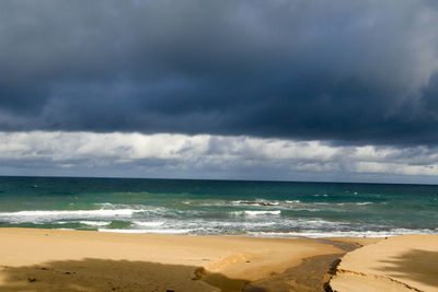 Scenic view of beach against cloudy sky