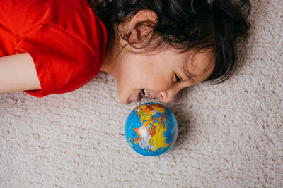 Smiling girl lying by globe 