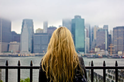 Rear view of woman looking at city buildings against sky