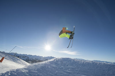 Male skier jumping against sky