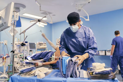 Doctor wearing face mask choosing clothes while standing with colleague at operation room