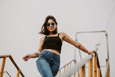 Portrait of young woman wearing sunglasses against railing