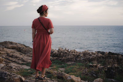 Full length rear view of woman looking at sea against sky