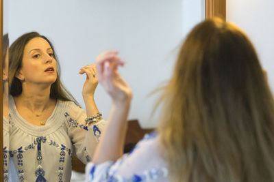 Woman looking into mirror at home