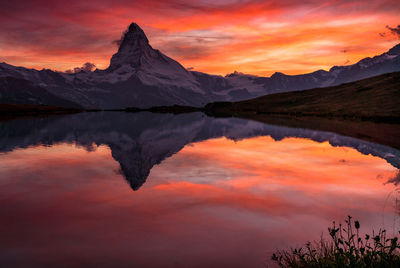 Scenic view of lake and mountains against orange sky