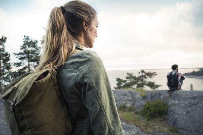 Side view of woman looking away while standing at lakeshore