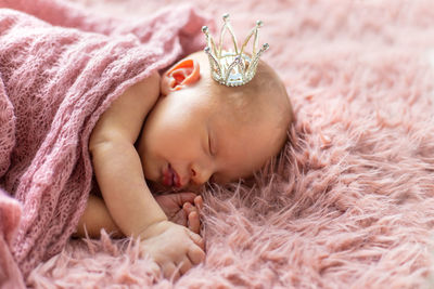 Baby girl sleeping on bed wearing crown