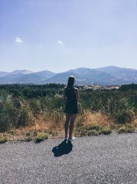 Rear view of woman standing on road against sky