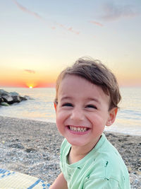 Portrait of boy at beach against sky during sunset