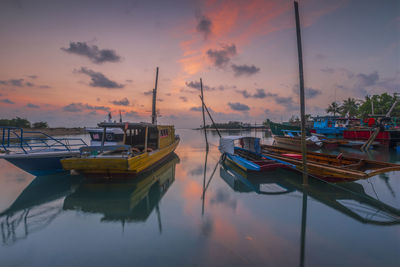 Boats moored at harbor during sunset