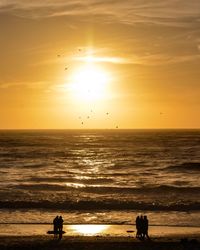 Silhouette people at beach during sunset