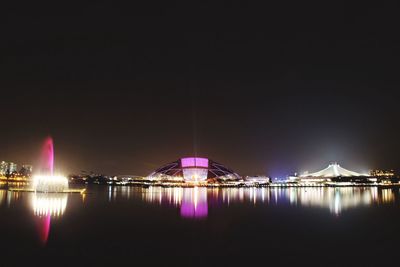 River by illuminated singapore national stadium against clear sky at night