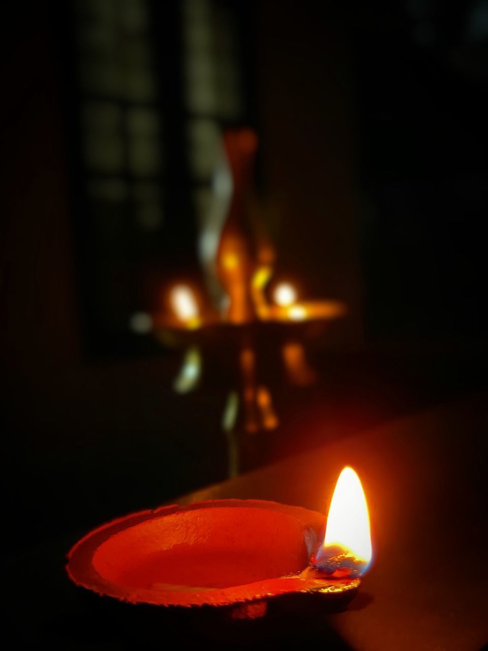 CLOSE-UP OF LIT CANDLE IN DARK ROOM