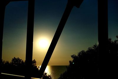 Silhouette trees by sea against sky during sunset