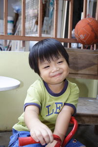 Cute smiling boy sitting on tricycle at home