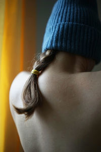 Rear view of shirtless woman holding braided hair
