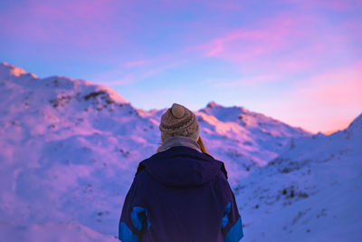Rear view of person on snowcapped mountain against sky during sunset