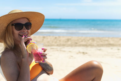 Portrait of young woman drinking water at beach