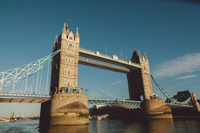 Low angle view of tower bridge over thames river against blue sky