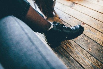 Low section of man wearing black shoes on hardwood floor at home