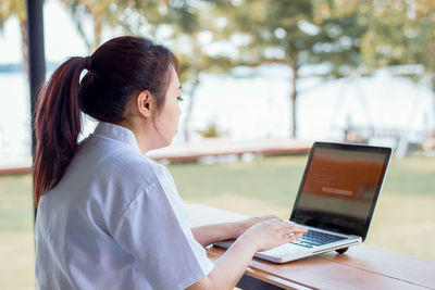 Side view of woman using mobile phone while sitting on table