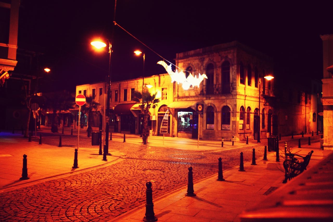 night, building exterior, illuminated, architecture, built structure, street light, street, lighting equipment, empty, city, cobblestone, incidental people, sidewalk, outdoors, house, absence, residential structure, bench, footpath, building