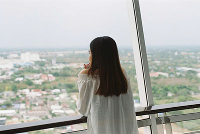 Woman looking at cityscape through window