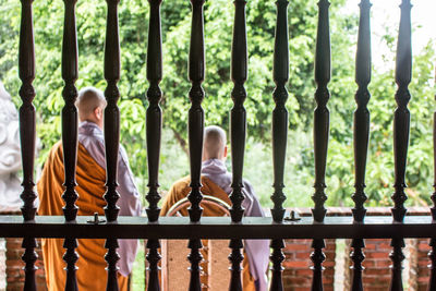 Rear view of monks seen through window at temple