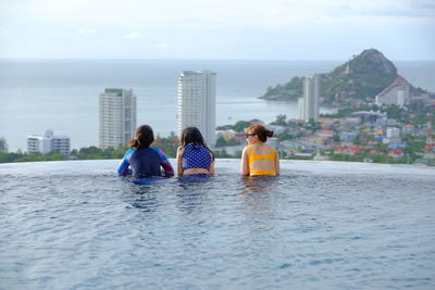 Rear view of friends relaxing in infinity pool