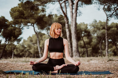 Full length of woman sitting by tree against plants