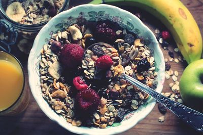 High angle view of breakfast cereals in bowl with juice on table