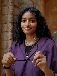 Portrait of smiling young woman standing against wall