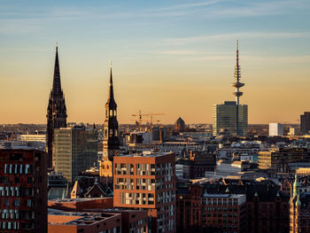 Modern buildings in city against sky during sunset