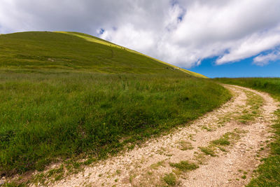 Road amidst field against sky