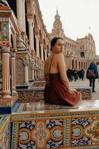 Side view of woman sitting on a building in seville. plaza de espana - spain square