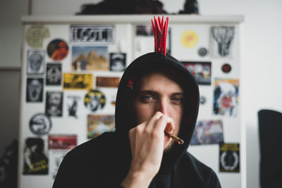 Portrait of punk man smoking against stickers wall