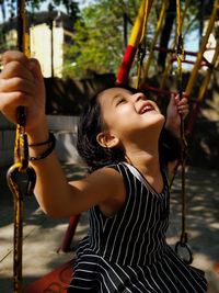 Low angle view of girl playing on swing at playground