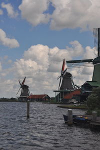 Stilt house on river by buildings against sky