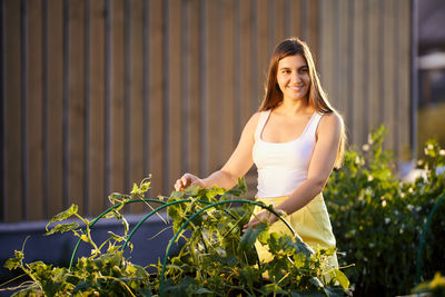 Portrait of young woman standing amidst plants